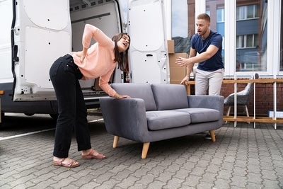 Woman Lifting Heavy New Sofa Furniture. Injury And Ache