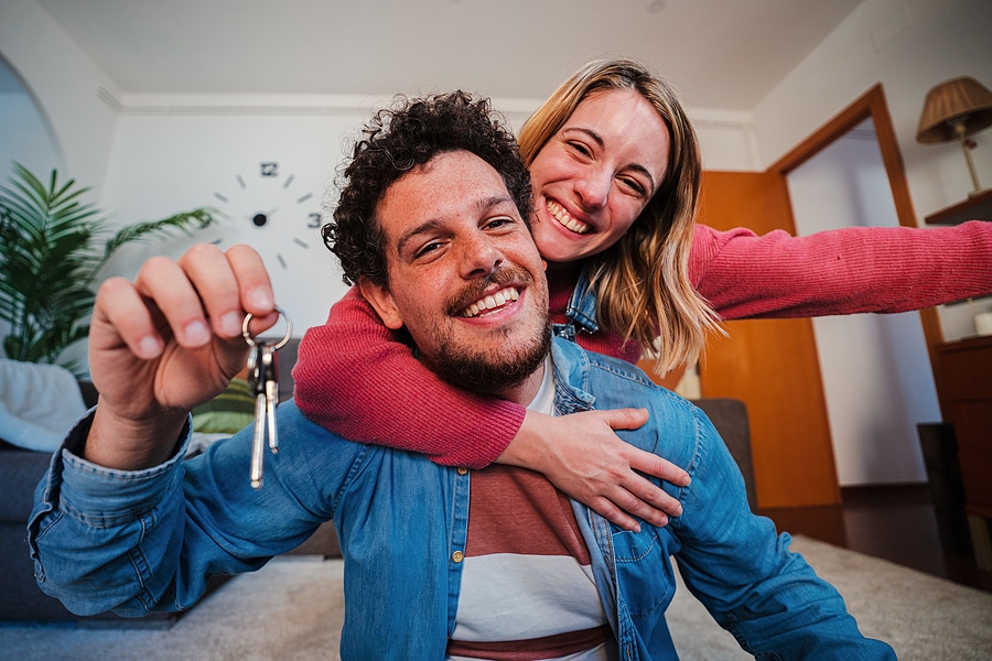 Young Couple Showing Keys Of Their First House