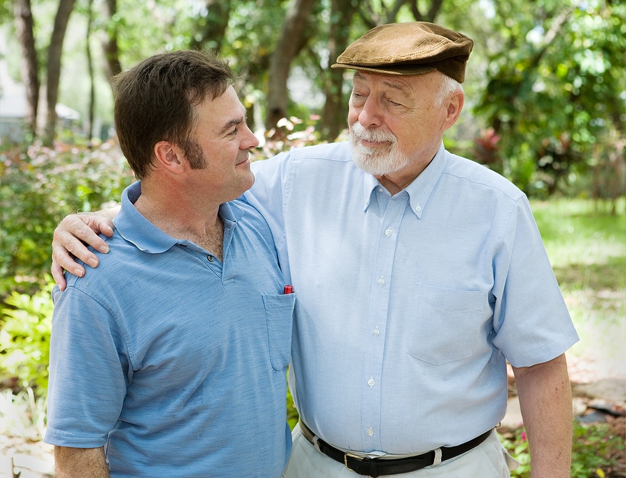 Father and adult son in the park together. The father is proud of his son.